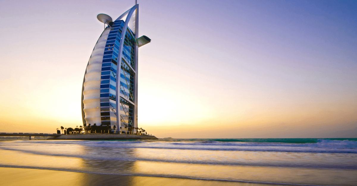 the Burj Al Arab hotel on the Dubai coastline at sunset, viewed from the beach